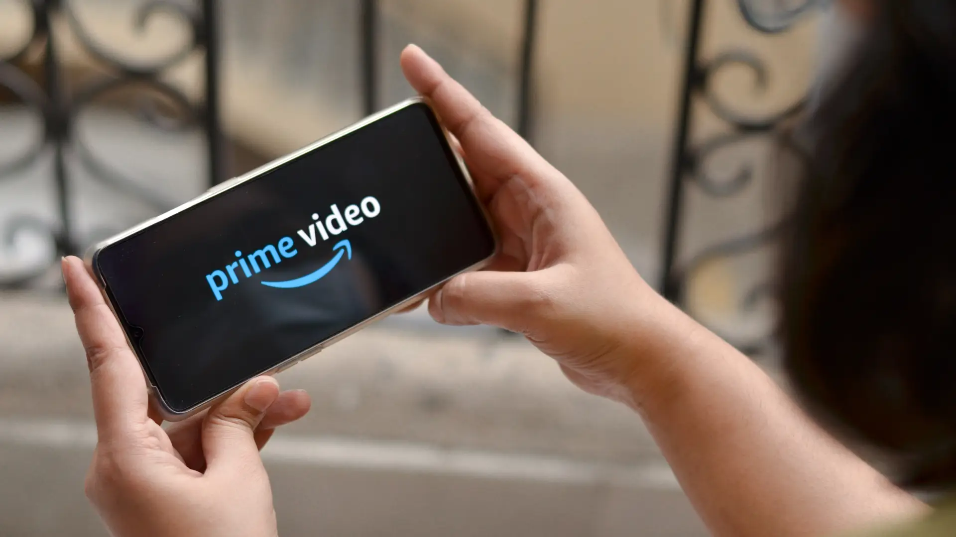 Manos de una persona sujetando un movil con el logo de prime video para hacer referencia a los dispositvos en los que se puede disfrutar