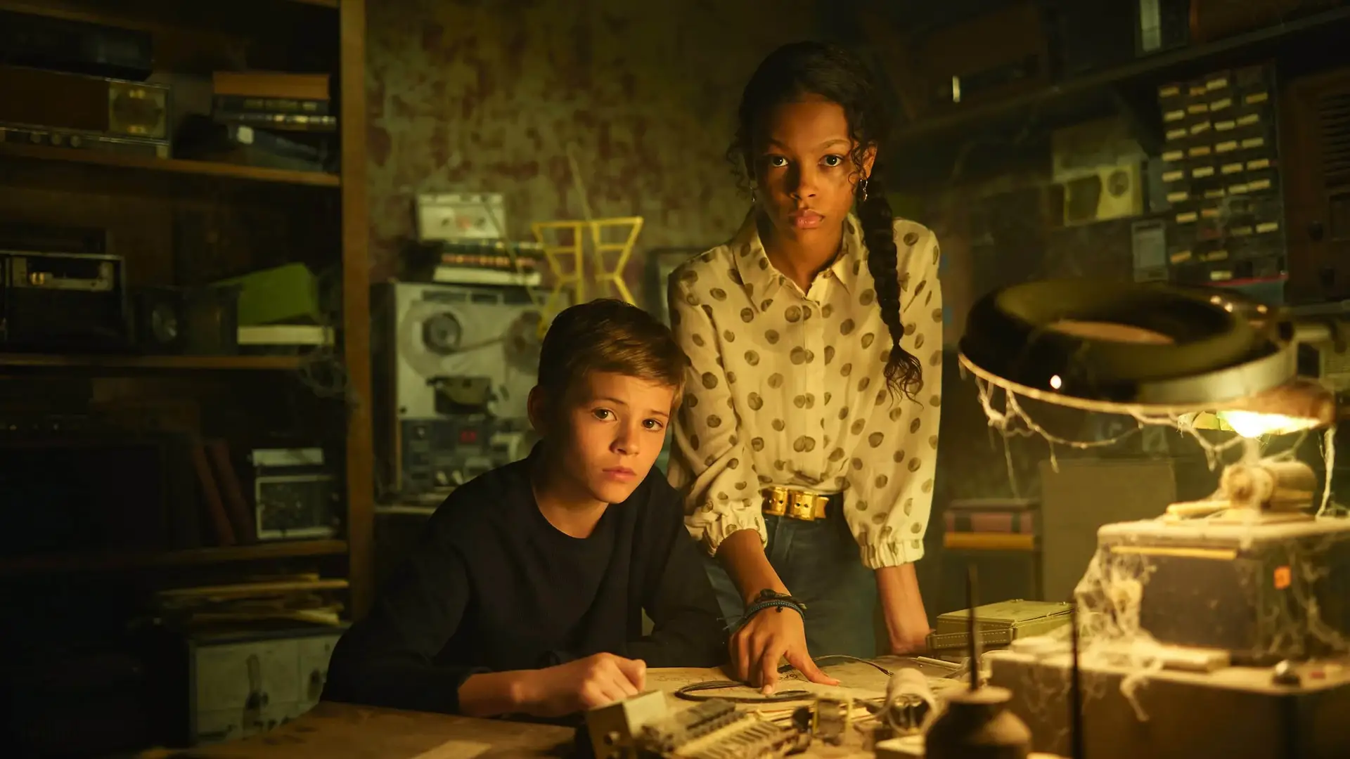 Dos niños con cara seria en una habitacion antigua que son los protagonistas de la serie Los Secretos de Sulpur Springs Dos niños con cara seria en una habitacion antigua que son los protagonistas de la serie Los Secretos de Sulpur Springs